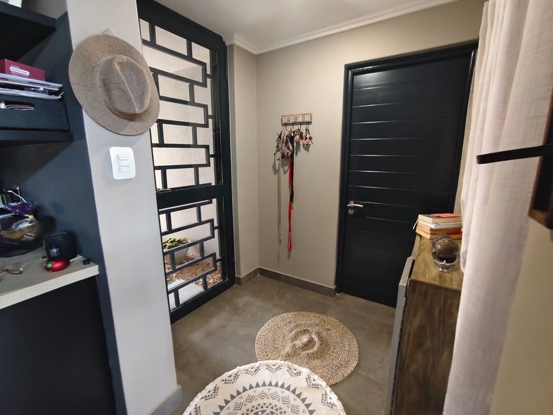 A functional entryway featuring a secure metal gate, modern tiled flooring, and a solid internal door leading to the rest of the home.