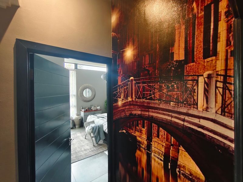 A view from a hallway featuring a large decorative wall mural, leading into a bedroom with natural light.