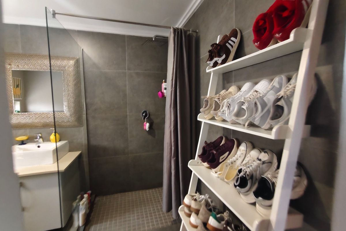 Modern bathroom featuring a walk-in shower with glass screen, vanity cabinet with basin, and contemporary grey wall tiling.