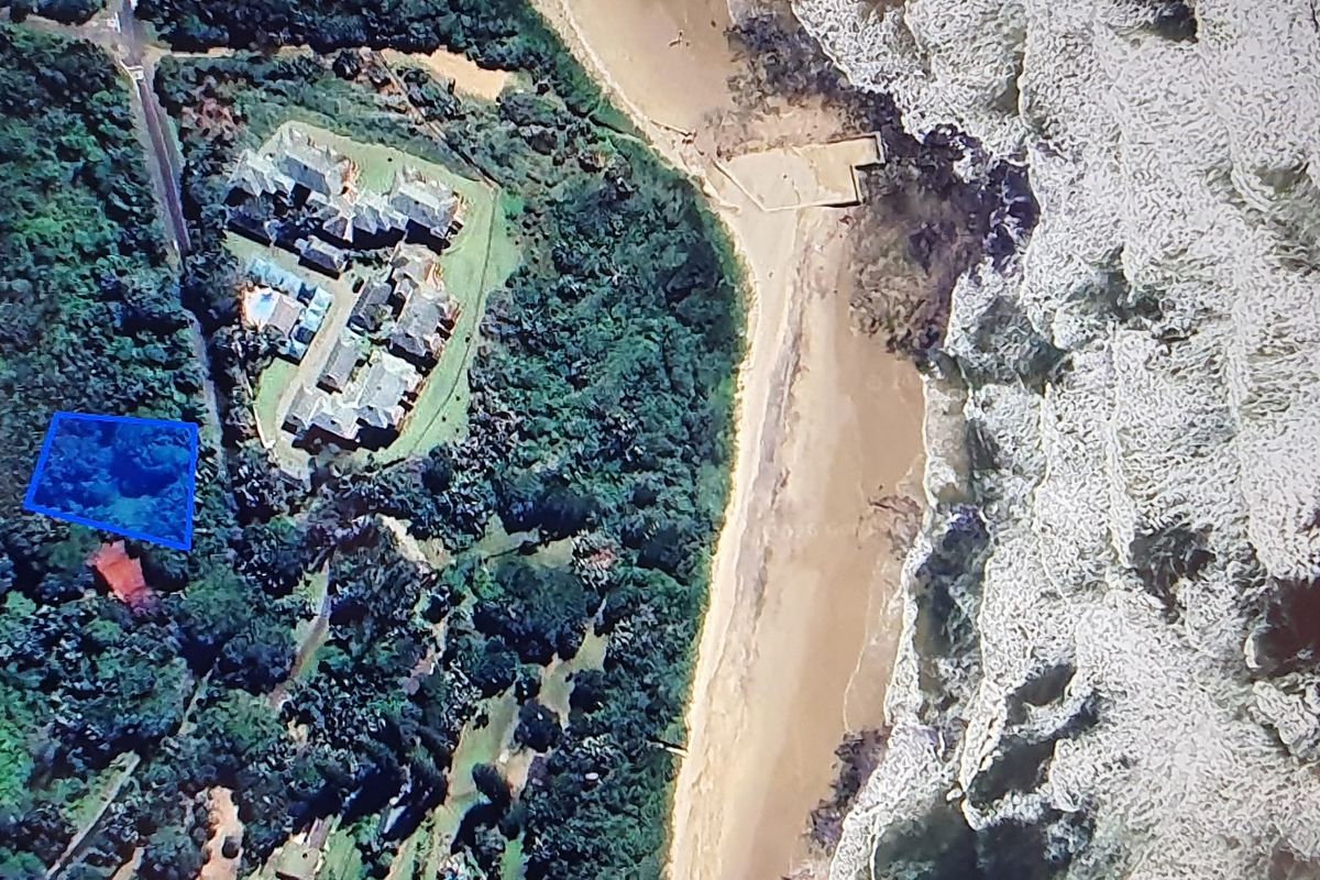 Aerial view of a vacant residential plot situated in a coastal area, highlighting its proximity to the beach and surrounding natural vegetation.