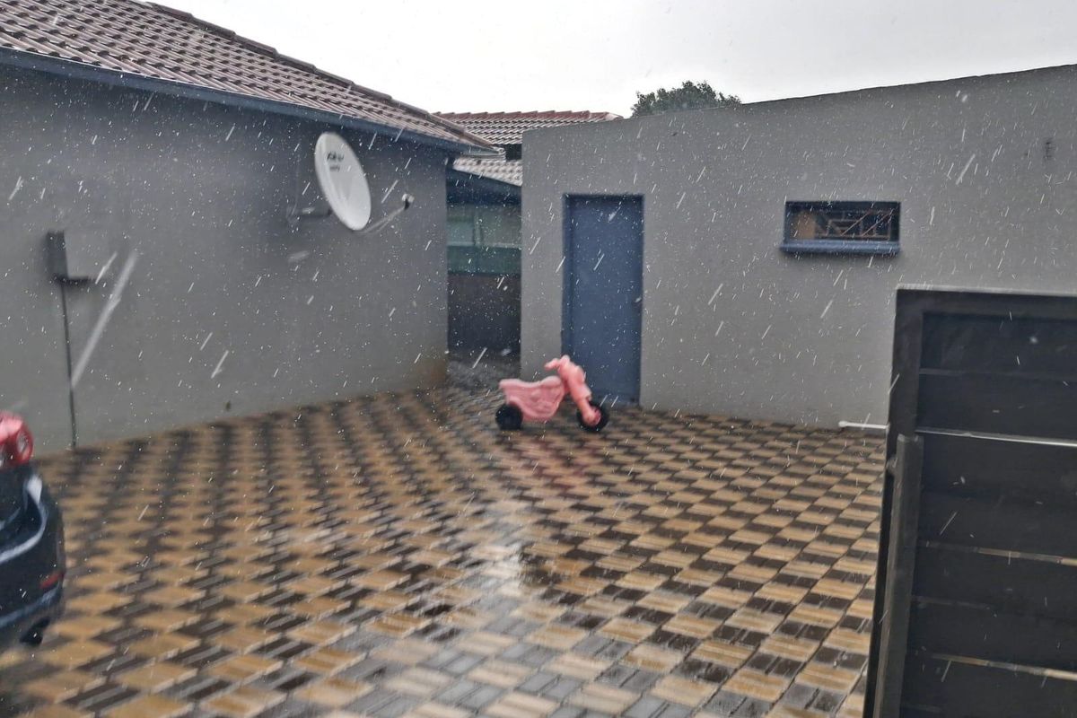 A paved rear courtyard area featuring a tiled roof structure, satellite dish, and secure access gate.