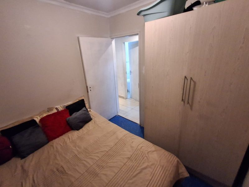 A functional bedroom featuring a built-in wardrobe and direct access to an adjoining bathroom.