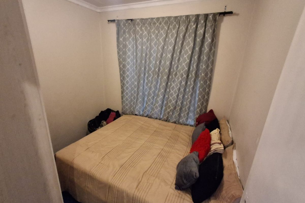 A compact bedroom featuring neutral walls and a fitted curtain rod, offering a functional space for a double bed.