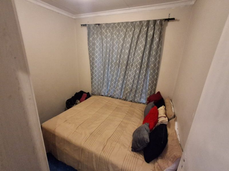 A compact bedroom featuring neutral walls and a fitted curtain rod, offering a functional space for a double bed.