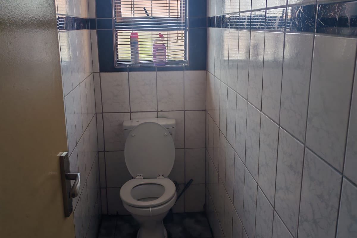 A compact, fully tiled guest bathroom featuring a standard toilet and a window with fitted blinds.