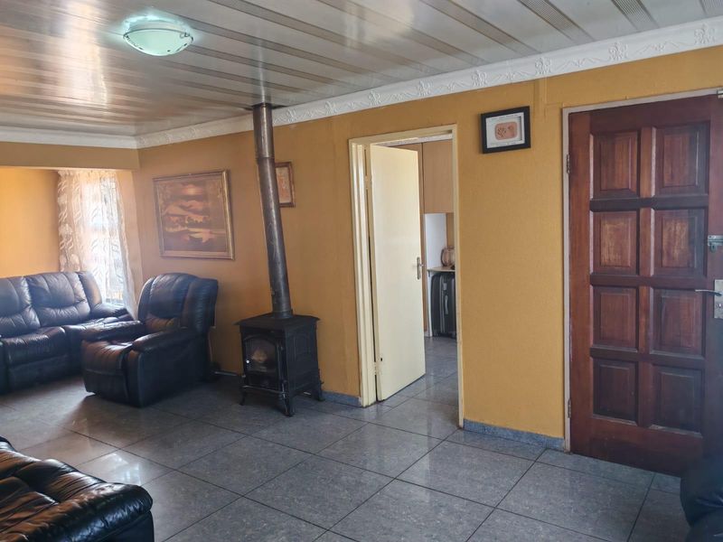Living room featuring a wood-burning stove, tiled flooring, and a panelled ceiling, with direct access to an adjacent room.