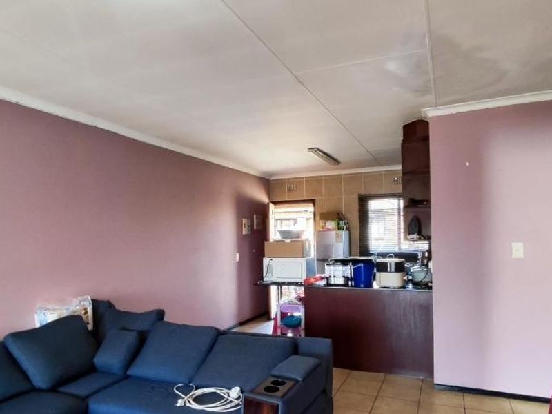 Open plan living and kitchen area featuring tiled flooring, breakfast counter, and coved ceilings, requiring cosmetic updates and ceiling repairs.