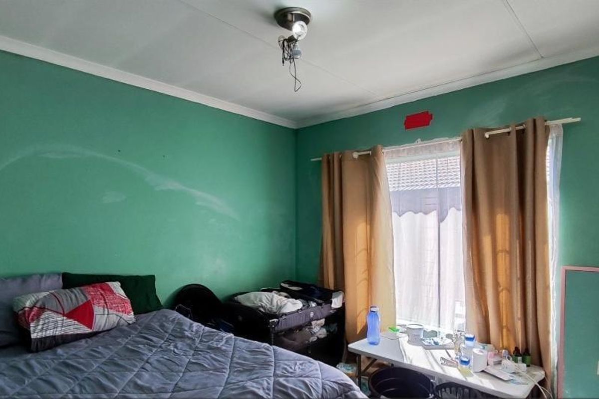 A bedroom featuring green painted walls, coving, and a built-in wardrobe, requiring cosmetic updates to improve the overall finish and appeal.