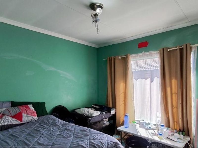 A bedroom featuring green painted walls, coving, and a built-in wardrobe, requiring cosmetic updates to improve the overall finish and appeal.