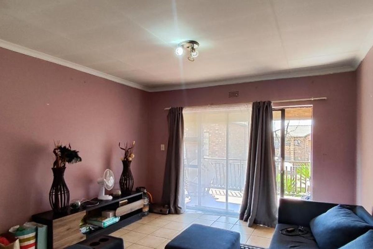 A living room featuring tiled flooring and a sliding glass door leading to an outdoor area, with potential for cosmetic updates to walls and finishes.