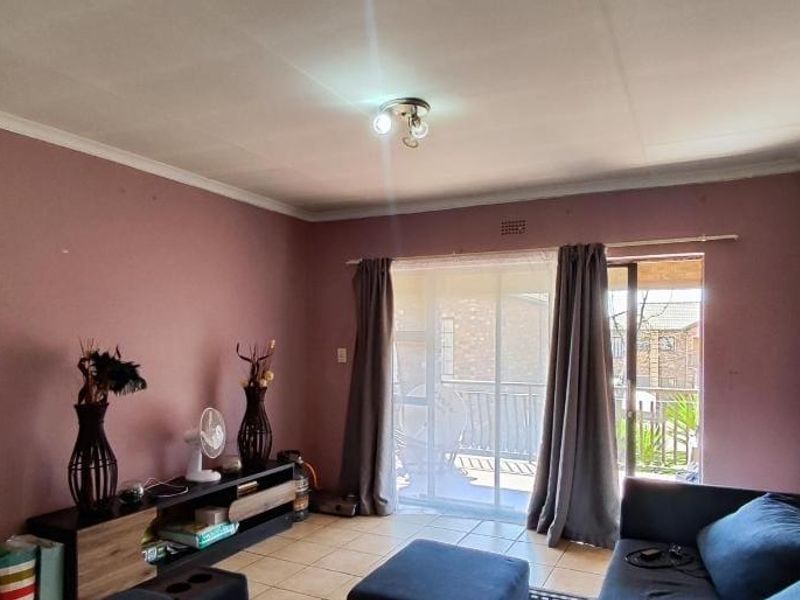 A living room featuring tiled flooring and a sliding glass door leading to an outdoor area, with potential for cosmetic updates to walls and finishes.