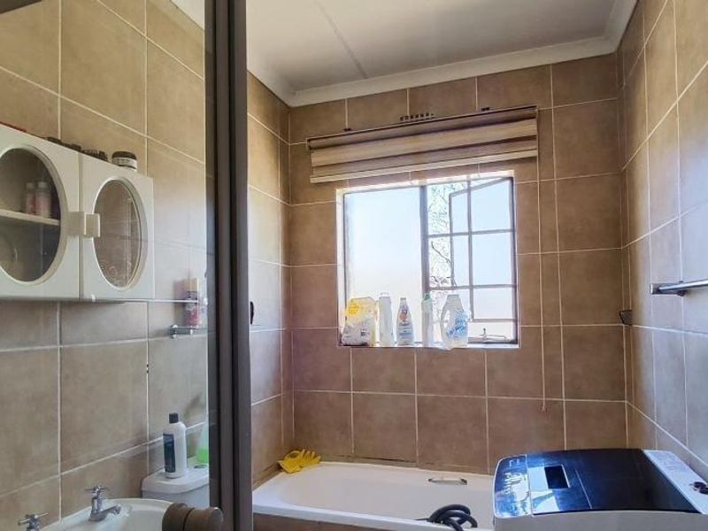 A functional bathroom featuring tiled walls, a bathtub, a toilet, and a basin, with a window providing natural light.