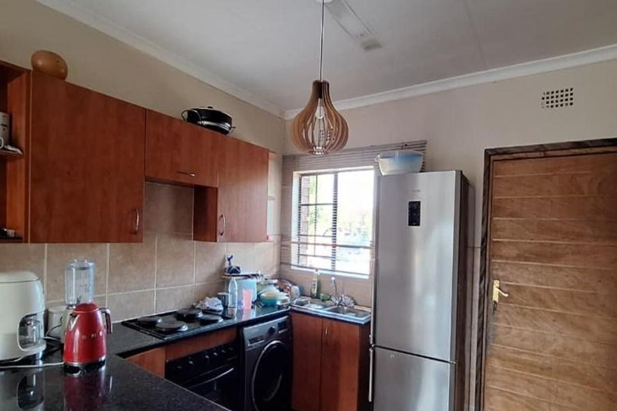 A functional kitchen featuring wooden cabinetry, granite countertops, a built-in oven and hob, and a tiled backsplash.