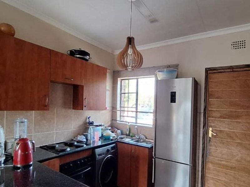 A functional kitchen featuring wooden cabinetry, granite countertops, a built-in oven and hob, and a tiled backsplash.