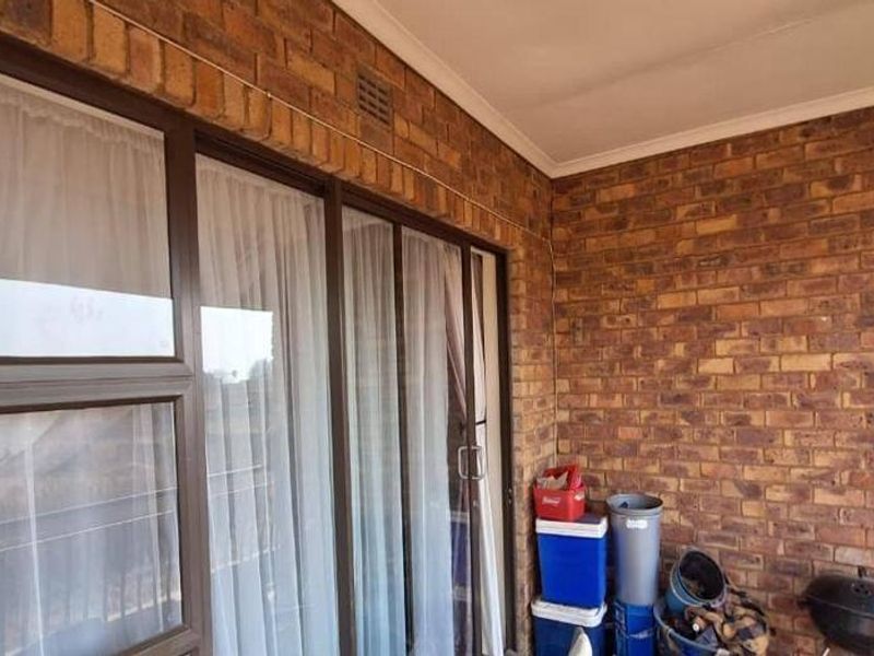 A covered balcony featuring face brick walls and large sliding glass doors, providing a functional outdoor space for the apartment.