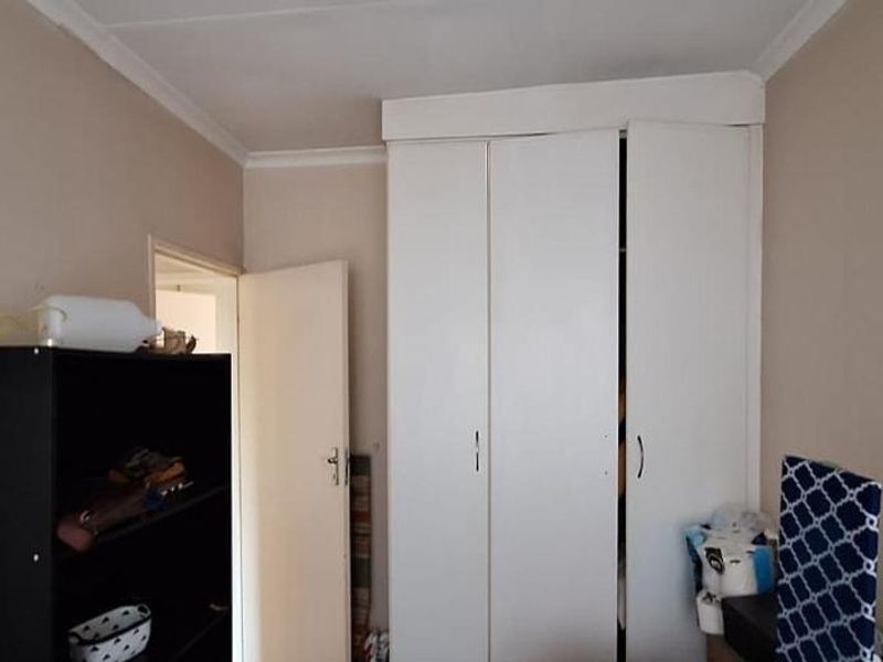 A bedroom featuring a white built-in wardrobe with multiple doors and ceiling cornice detailing.