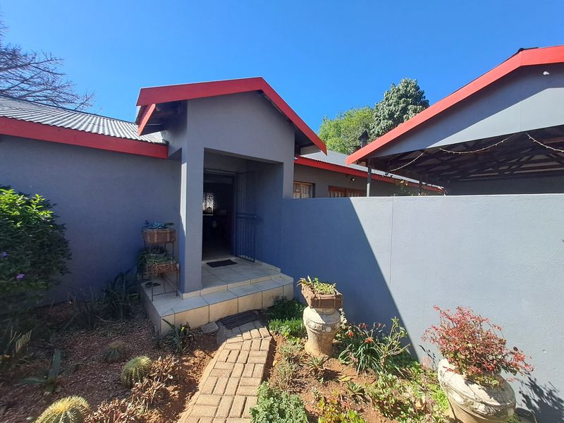 Front entrance of the house featuring a paved walkway, tiled steps, and a covered entryway with a security gate.