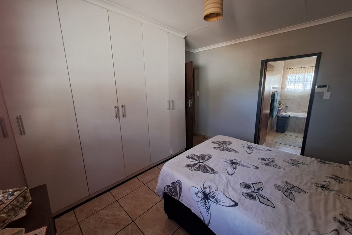 Bedroom featuring built-in cupboards, tiled flooring, and direct access to an en-suite bathroom.