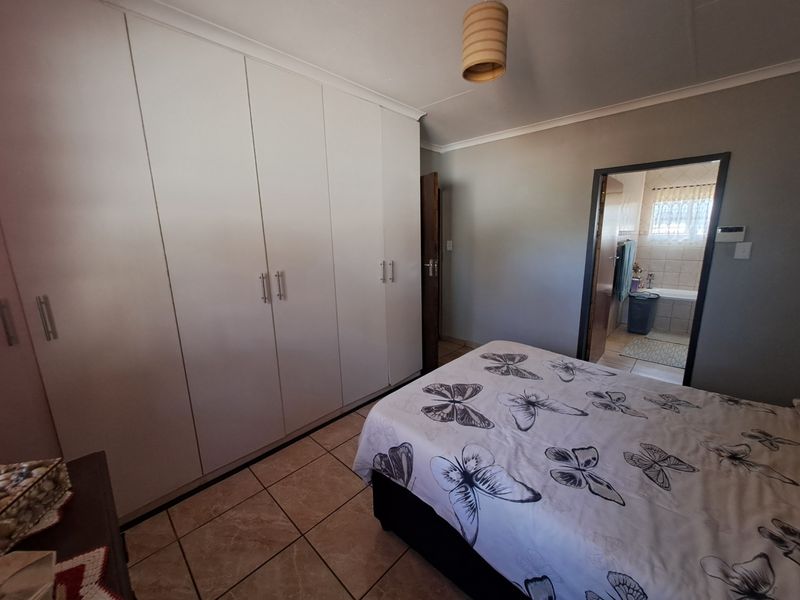 Bedroom featuring built-in cupboards, tiled flooring, and direct access to an en-suite bathroom.