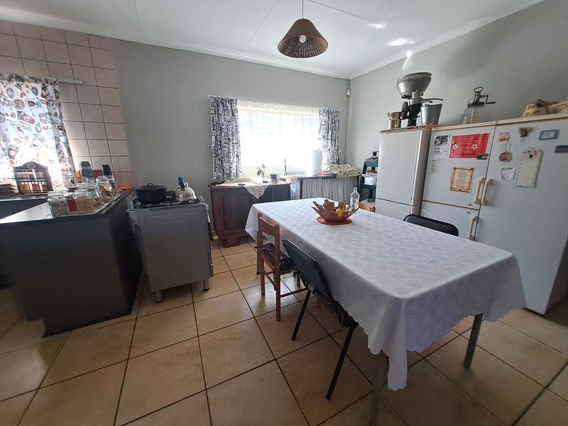 A functional kitchen area featuring tiled flooring, a tiled splashback, and a freestanding stove, offering a practical layout for daily meal preparation.