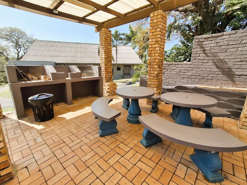 Covered outdoor patio area featuring a built-in braai, brick pillars, and paved flooring, ideal for outdoor entertaining.
