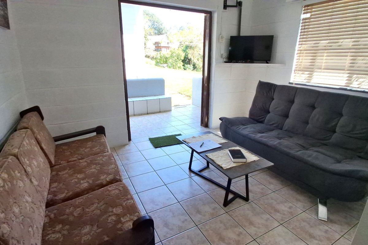 A living room featuring tiled flooring, exposed blockwork walls, and a sliding door providing direct access to an outdoor patio area.