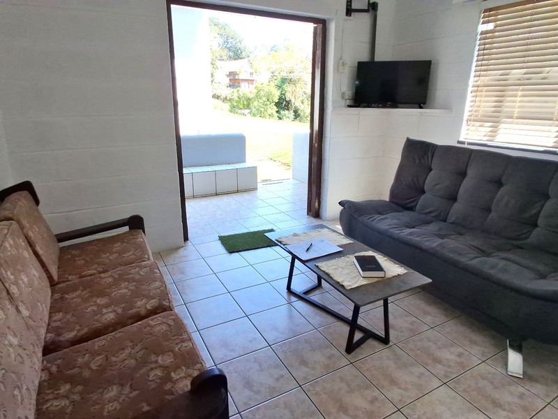 A living room featuring tiled flooring, exposed blockwork walls, and a sliding door providing direct access to an outdoor patio area.