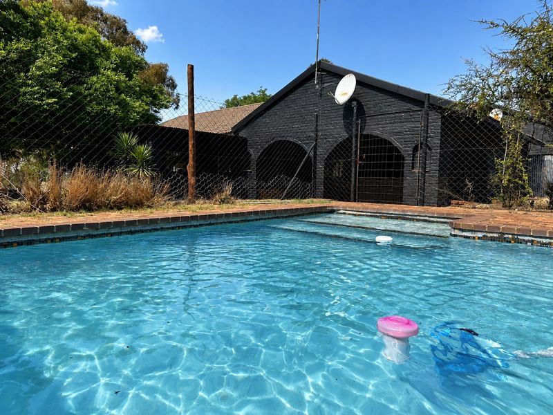Outdoor swimming pool area featuring brick coping and a view of the rear building facade with arched architectural details.