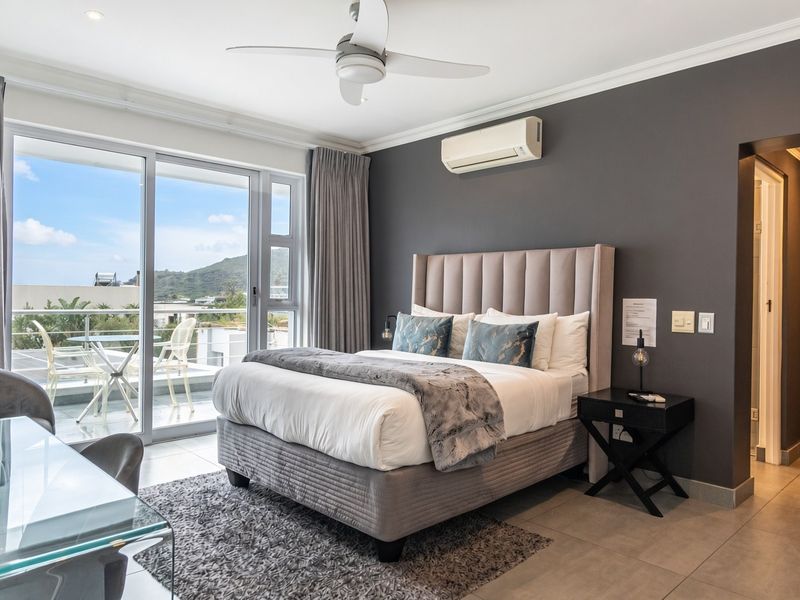 A well-maintained bedroom featuring tiled floors, a ceiling fan, split-system air conditioning, and sliding glass doors leading to a private balcony.