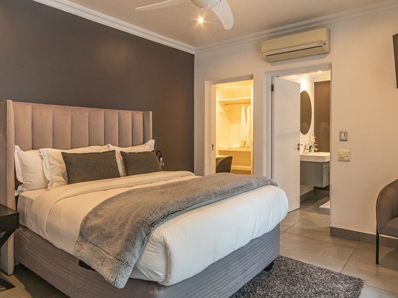 A well-maintained bedroom featuring a neutral color palette, en-suite bathroom access, walk-in closet, and integrated climate control.