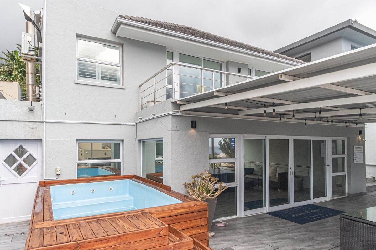 Rear exterior view featuring a covered patio area, built-in jacuzzi, and sliding glass doors leading into the residence.