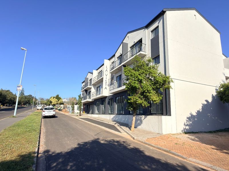 Exterior view of the La Vista apartment complex, showcasing the modern multi-story facade, balconies, and adjacent street access.