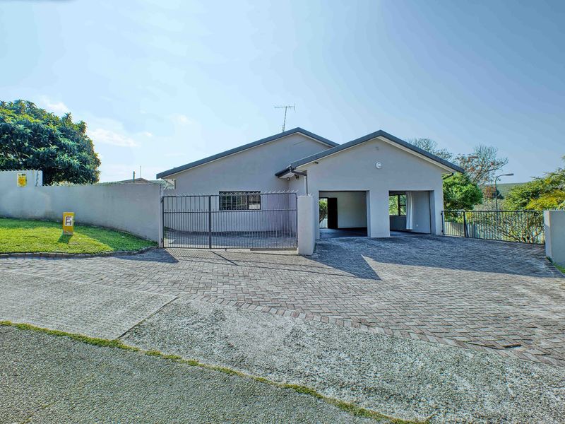 Front exterior view of a residential house featuring a paved driveway, double garage, and secure perimeter walling.