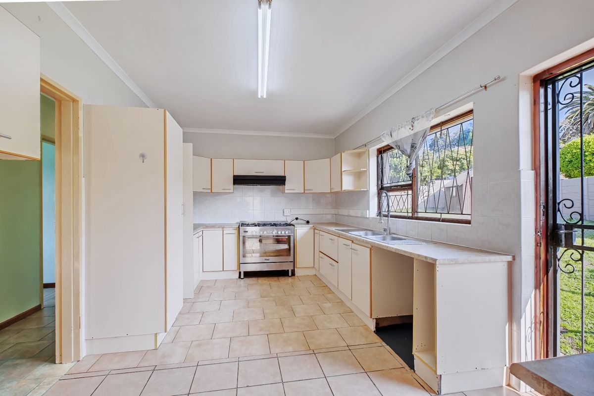 A functional kitchen featuring built-in cabinetry, a gas stove with extractor, and a double basin sink, with direct access to the garden.