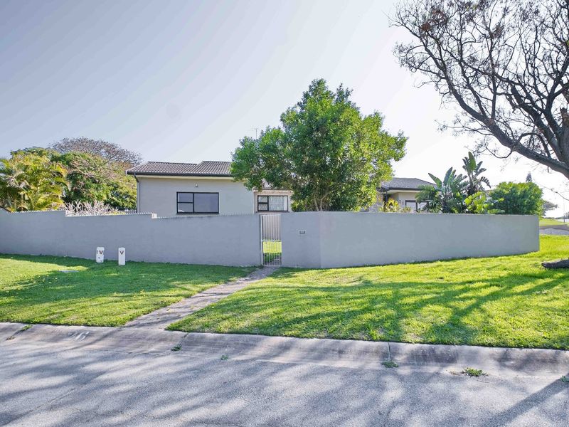 Front view of the property featuring a secure perimeter wall, pedestrian gate, and a well-maintained lawn area.