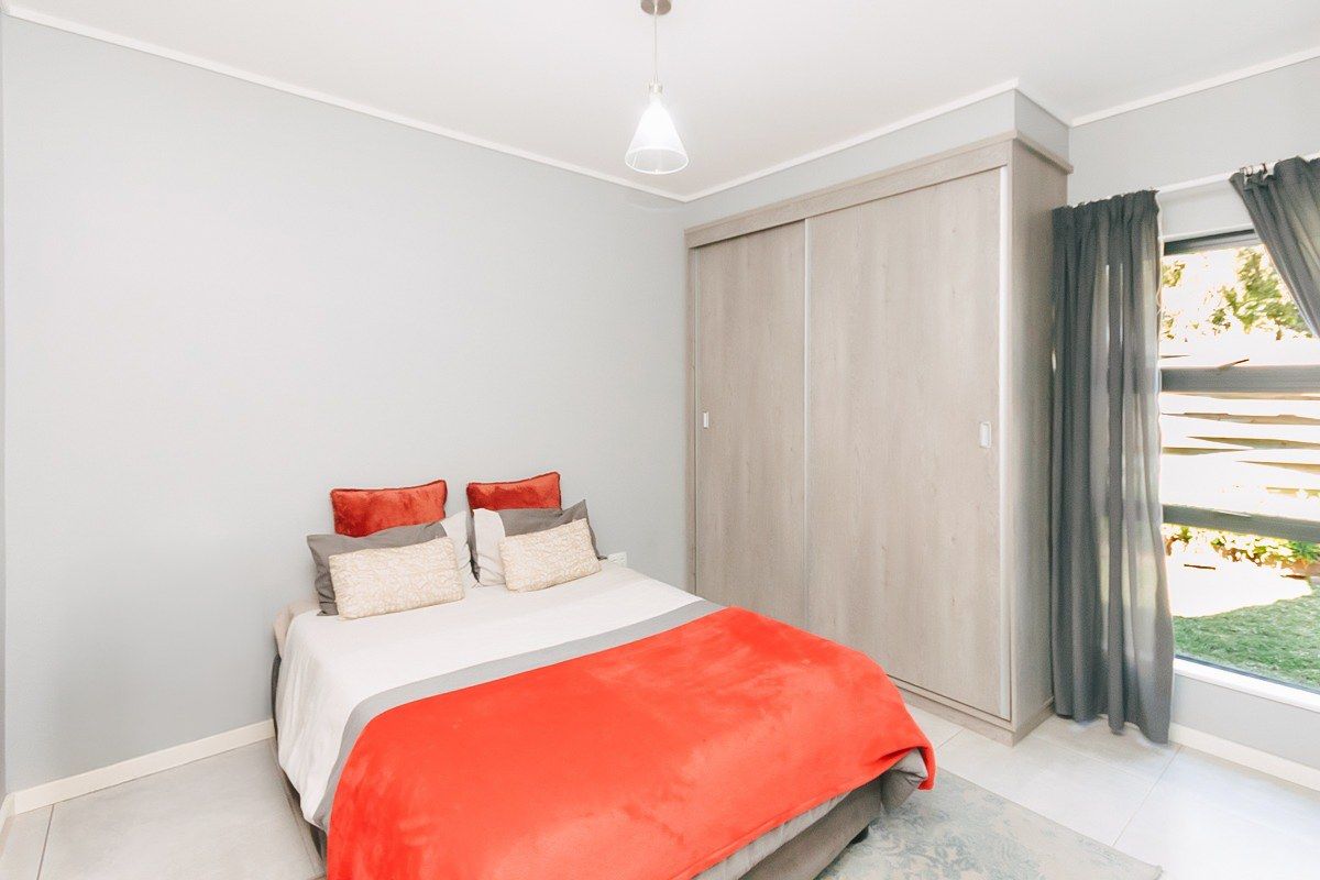 A well-maintained bedroom featuring neutral tiled flooring, a modern built-in wardrobe with sliding doors, and clean wall finishes.