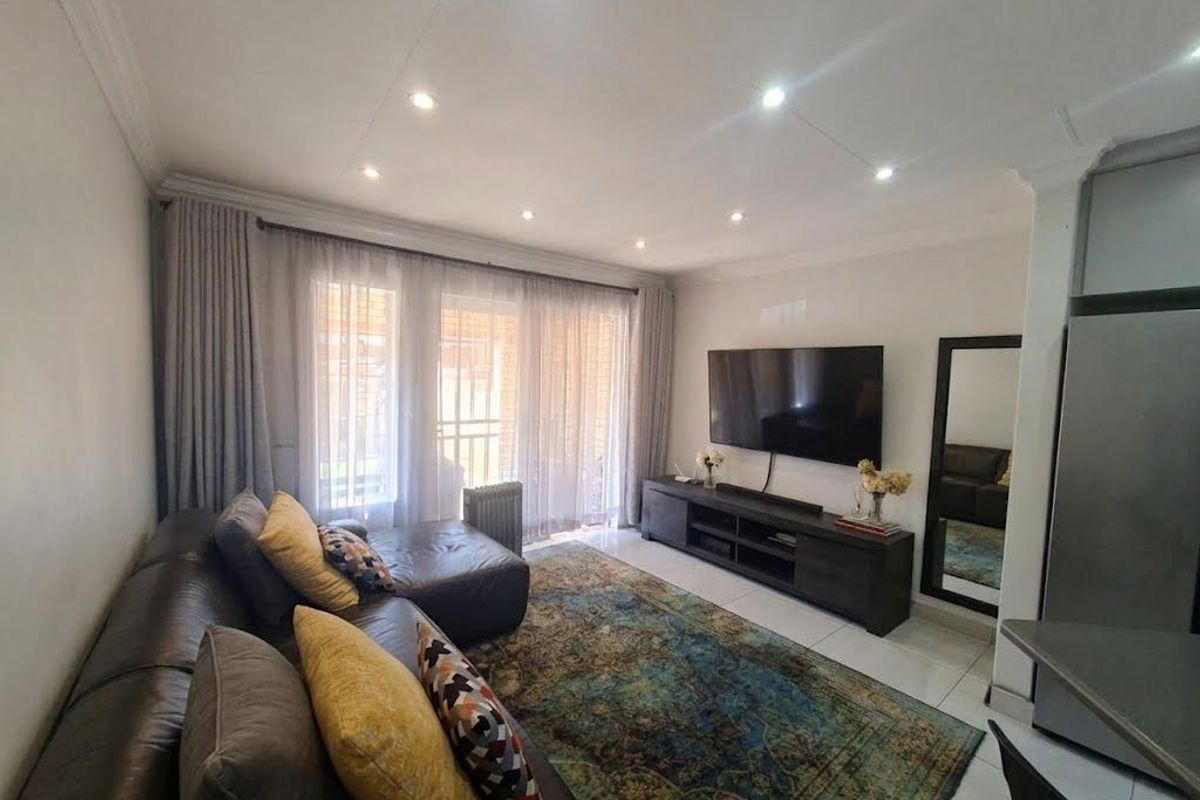 A well-maintained living room featuring tiled floors, recessed downlighting, and large sliding glass doors that provide ample natural light.
