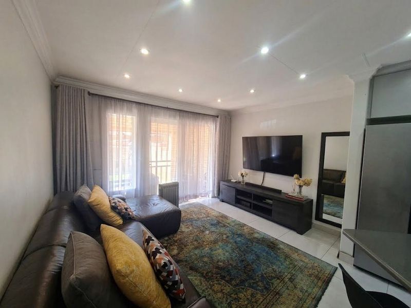 A well-maintained living room featuring tiled floors, recessed downlighting, and large sliding glass doors that provide ample natural light.
