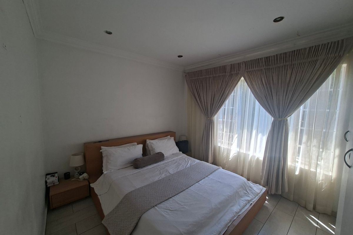 A bedroom featuring tiled flooring, recessed downlighting, and large windows with fitted curtain tracks.