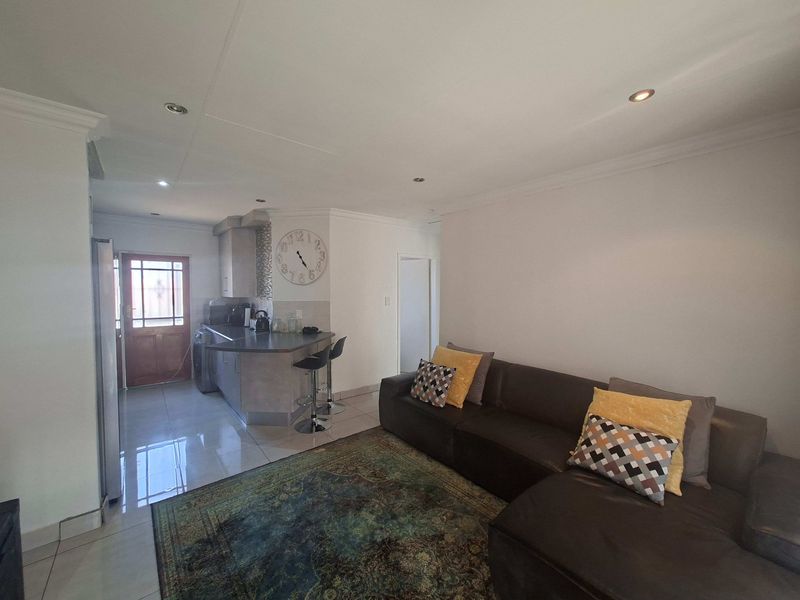 Open plan living area featuring tiled floors, recessed lighting, and a compact kitchen with a breakfast bar and integrated extractor fan.