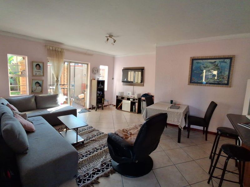 Open-plan living and dining area featuring tiled flooring, a breakfast bar, and a sliding glass door providing access to the exterior.