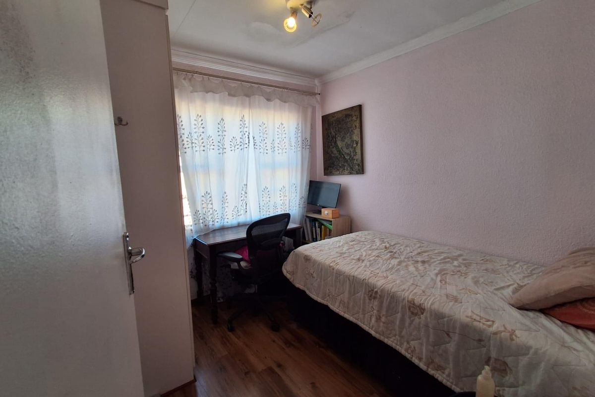 A compact bedroom featuring laminate flooring, a built-in cupboard, and coving, with visible water staining on the ceiling requiring attention.