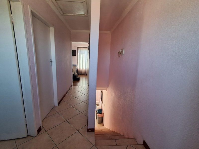 A functional hallway featuring tiled flooring and a staircase leading to a lower level, with access to adjacent rooms.