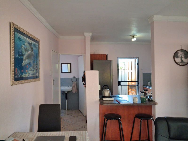 Open plan living area featuring a breakfast bar, kitchen access, and a separate bathroom with a pedestal basin.