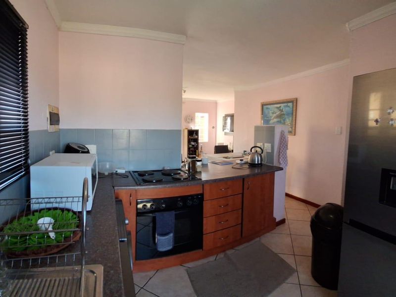 Functional kitchen featuring built-in oven, electric hob, laminate cabinetry, and tiled splashback, offering a practical layout with direct access to the living area.
