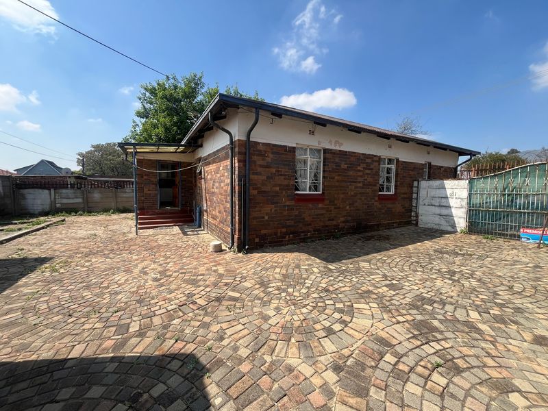 Rear view of the house featuring a large brick-paved courtyard, face brick exterior walls, and secure boundary fencing.