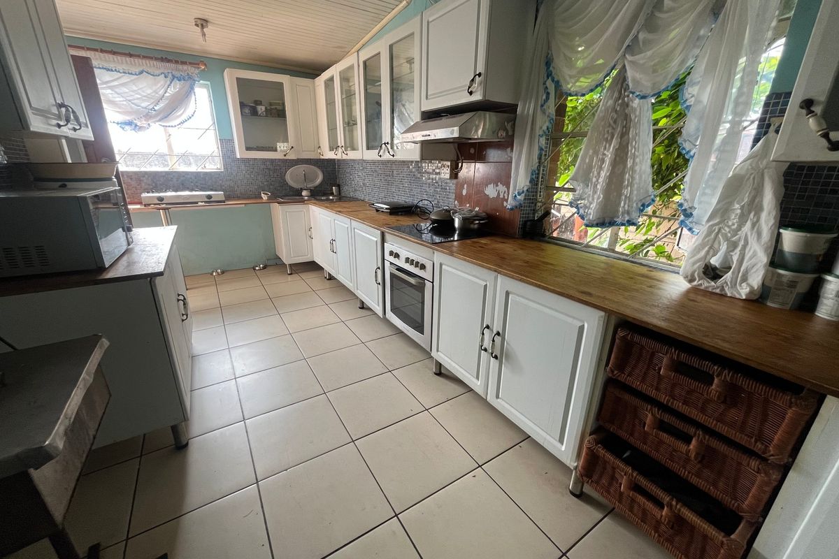 A functional kitchen featuring white cabinetry, wooden countertops, a built-in oven, and a mosaic tile backsplash with tiled flooring throughout.