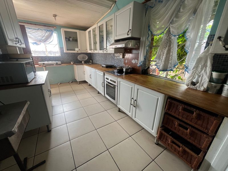 A functional kitchen featuring white cabinetry, wooden countertops, a built-in oven, and a mosaic tile backsplash with tiled flooring throughout.