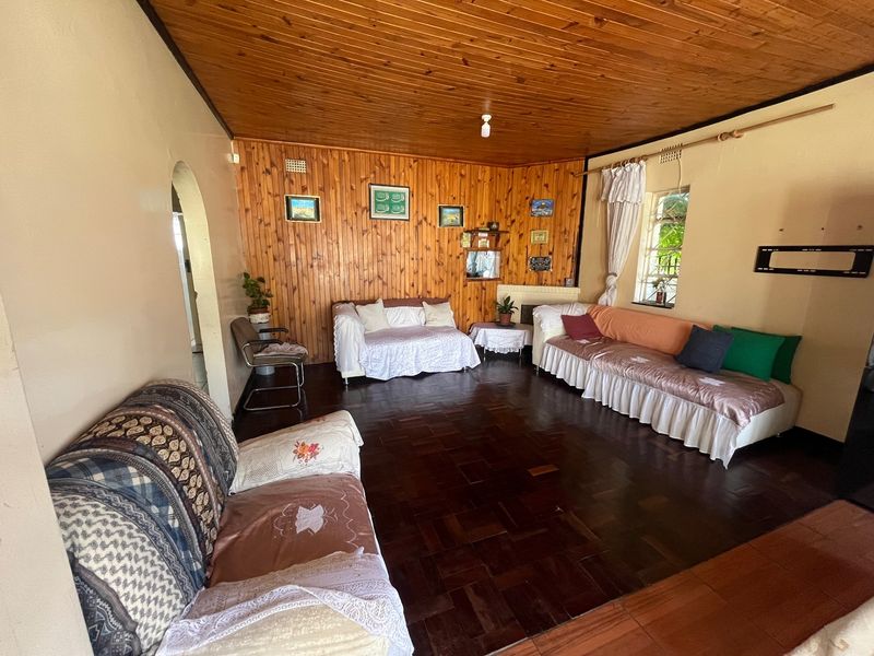 Spacious living room featuring traditional timber wall paneling, a warm timber ceiling, and classic parquet flooring with an integrated fireplace.