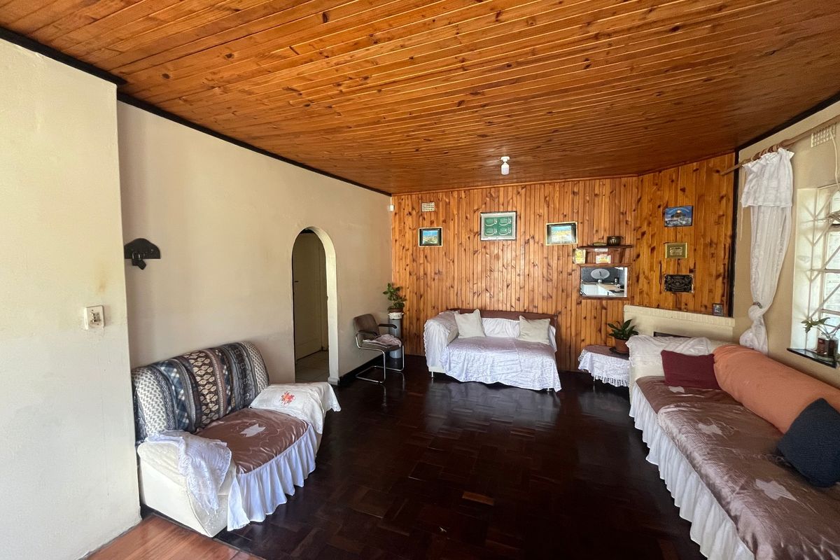 Spacious living room featuring traditional timber ceiling and wall paneling with classic parquet flooring and an arched entryway.